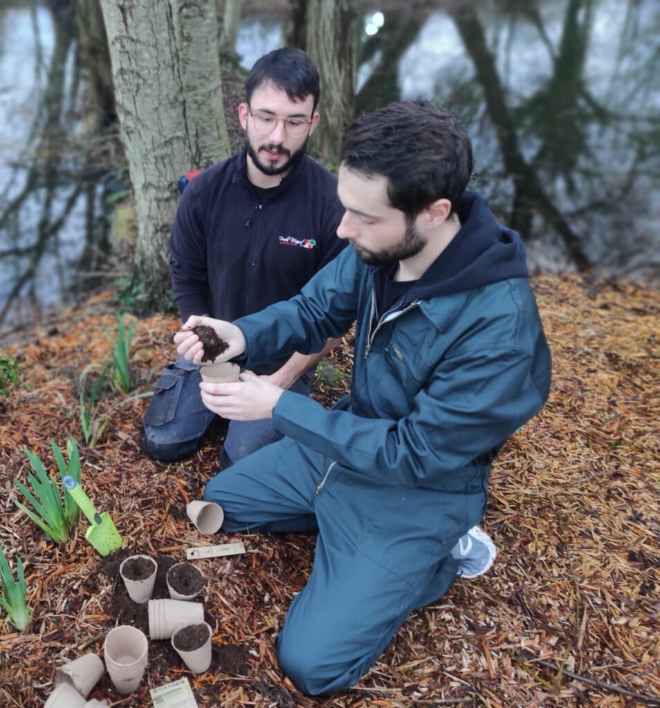 Deux personnes assises dans un jardin, en train de planter et de discuter autour des végétaux