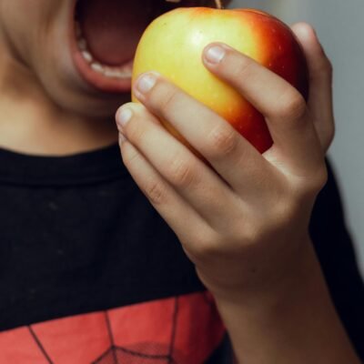 Enfant croquant dans une pomme grâce aux fruits obtenus par la pollinisation